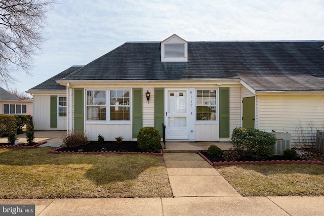 view of front facade with central air condition unit, board and batten siding, and a front lawn