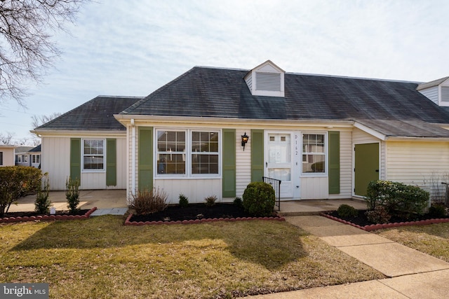 cape cod home with a front lawn, a patio area, and board and batten siding