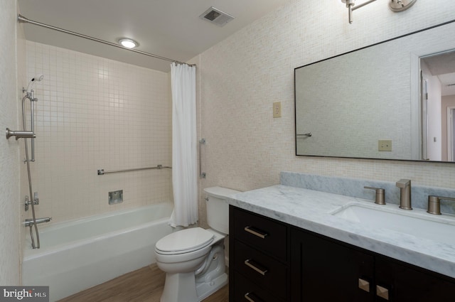 bathroom with visible vents, toilet, shower / bath combo with shower curtain, wood finished floors, and vanity