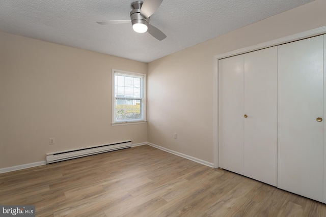 unfurnished bedroom with baseboards, light wood finished floors, a closet, a textured ceiling, and baseboard heating