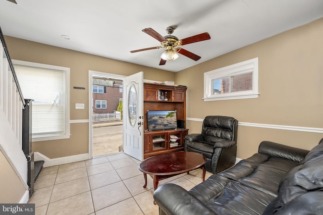 living room with light tile patterned flooring, baseboards, stairs, and ceiling fan