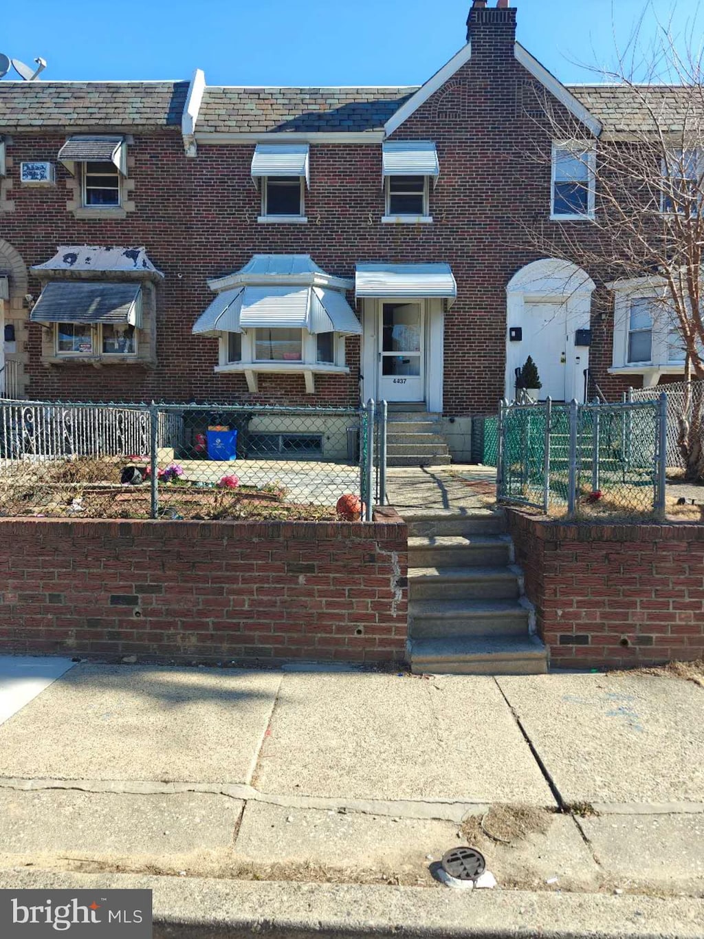 multi unit property with brick siding, a chimney, and fence