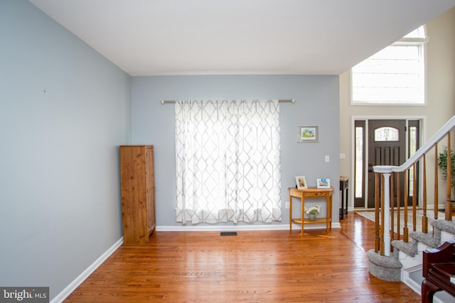 entrance foyer featuring stairway, visible vents, baseboards, and wood finished floors