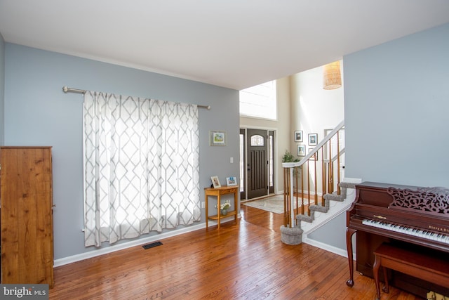 entryway with visible vents, wood-type flooring, baseboards, and stairs