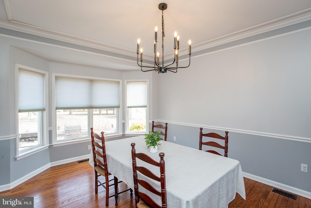 dining area with a notable chandelier, baseboards, visible vents, and wood finished floors