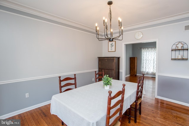 dining area featuring baseboards, a notable chandelier, wood finished floors, and ornamental molding