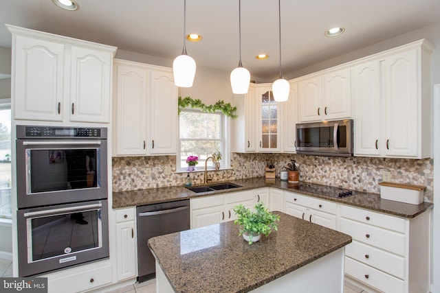 kitchen with a sink, dark stone countertops, tasteful backsplash, white cabinetry, and stainless steel appliances