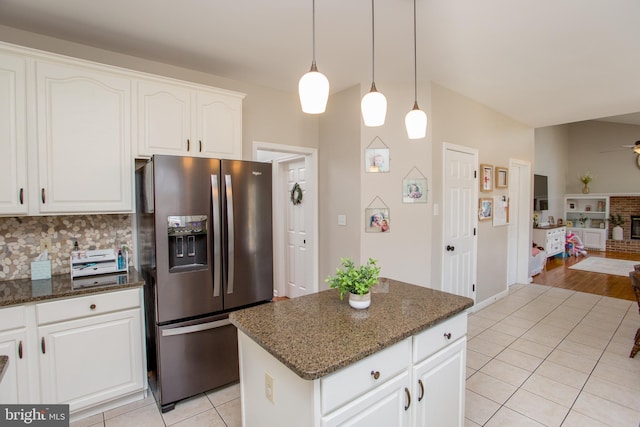 kitchen with dark stone counters, light tile patterned flooring, stainless steel fridge with ice dispenser, decorative backsplash, and a center island