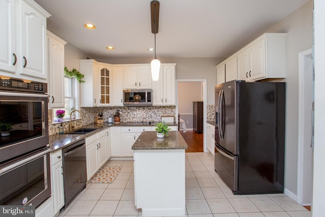 kitchen featuring a sink, tasteful backsplash, a center island, dark stone counters, and appliances with stainless steel finishes