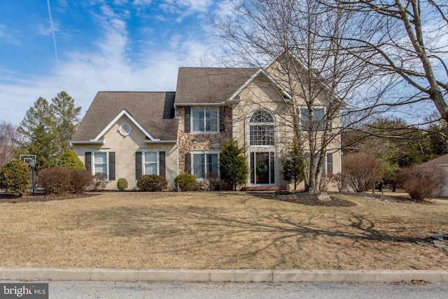 view of front of property featuring stucco siding, stone siding, a front yard, and a shingled roof