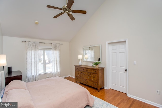 bedroom with ceiling fan, light wood-style floors, baseboards, and high vaulted ceiling