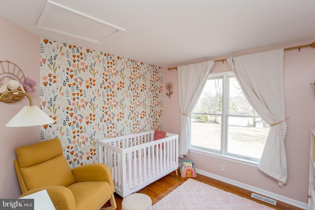 bedroom featuring visible vents, multiple windows, attic access, and a nursery area