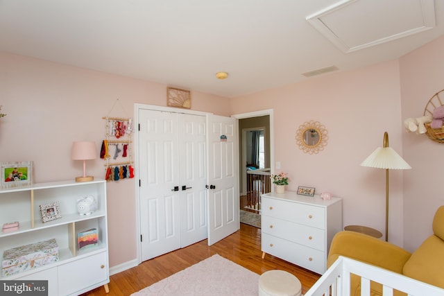 bedroom featuring attic access, wood finished floors, visible vents, and a closet