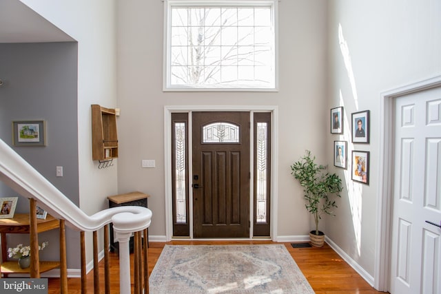 foyer with a high ceiling, baseboards, and light wood finished floors