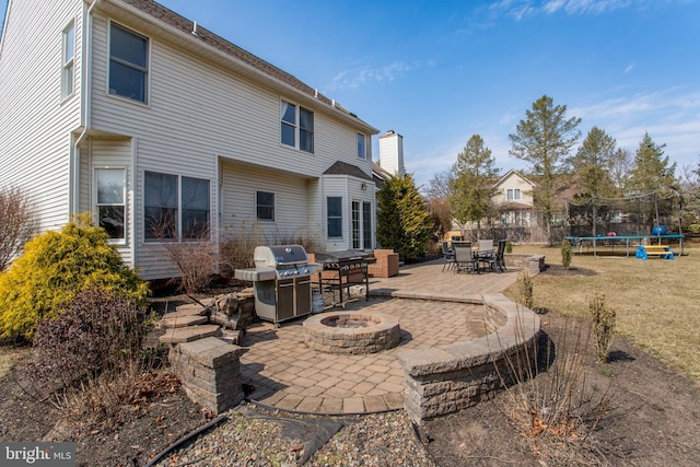 rear view of house with a yard, a fire pit, a trampoline, and a patio area