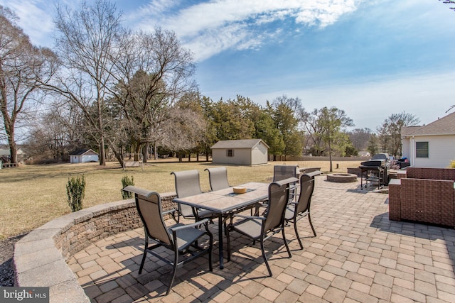 view of patio / terrace featuring an outdoor structure, outdoor dining space, and an outdoor fire pit