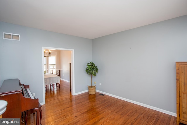 interior space with light wood-style flooring, a notable chandelier, baseboards, and visible vents