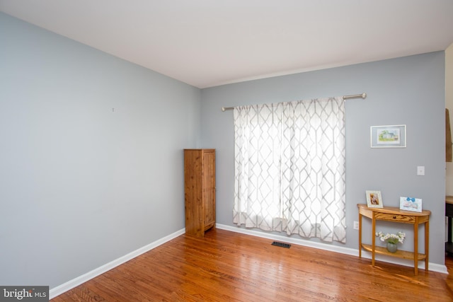 empty room featuring visible vents, baseboards, and wood finished floors