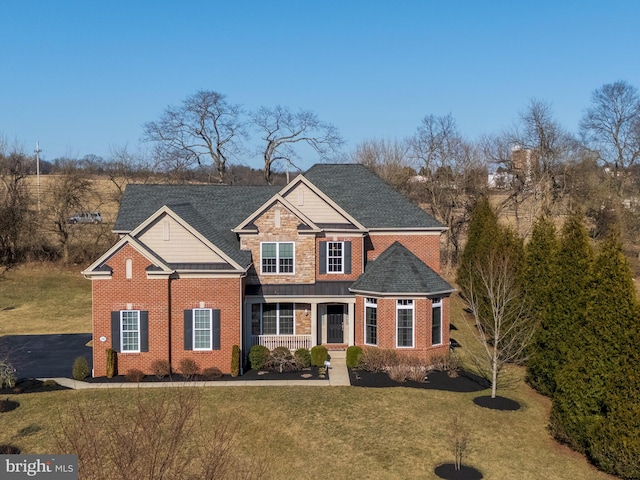 view of front of property with brick siding, stone siding, a shingled roof, and a front lawn