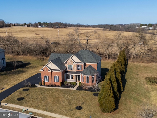 view of front facade featuring brick siding, a rural view, and a front yard