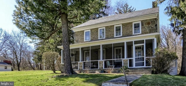 view of front of home featuring a front yard and a sunroom