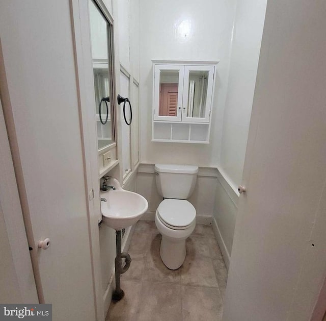 half bath with tile patterned flooring and toilet