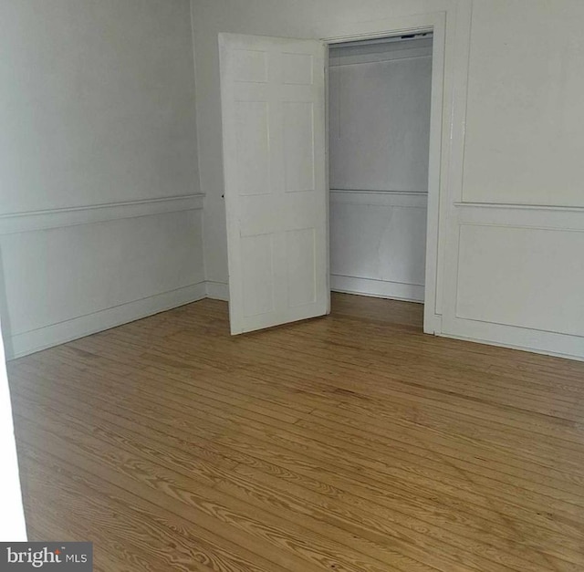 unfurnished bedroom featuring a closet, baseboards, and wood finished floors