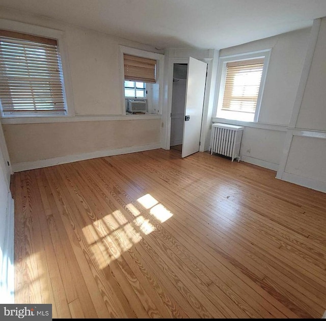 unfurnished bedroom featuring light wood finished floors, radiator, and baseboards