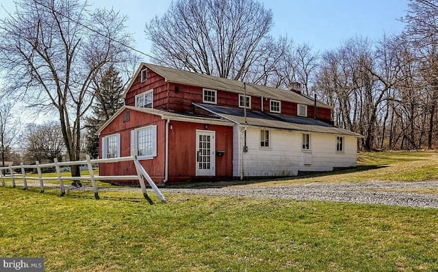 rear view of property with a lawn and fence