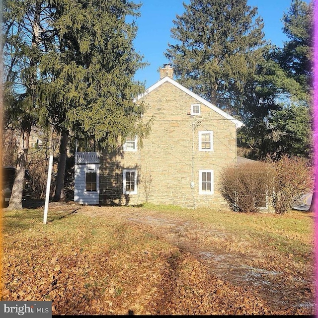 view of side of property with a yard and a chimney