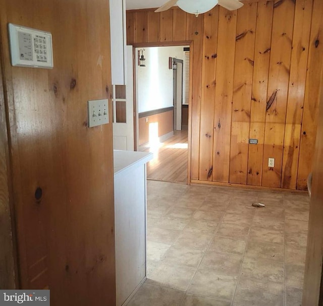 hall featuring light floors and wood walls