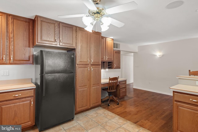 kitchen with light countertops, brown cabinetry, and freestanding refrigerator