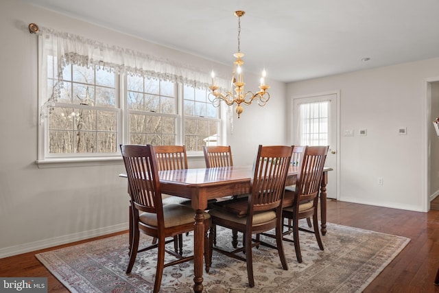 dining space featuring baseboards, an inviting chandelier, and wood finished floors