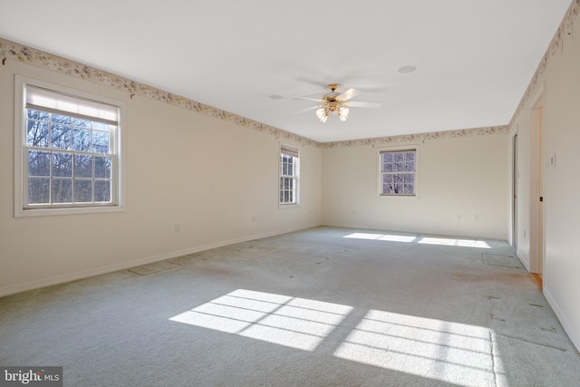 empty room featuring light carpet, a ceiling fan, and baseboards