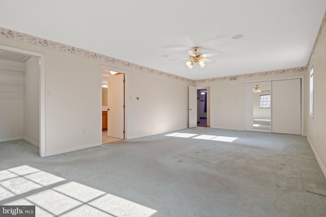 interior space with visible vents, a walk in closet, baseboards, light carpet, and a closet