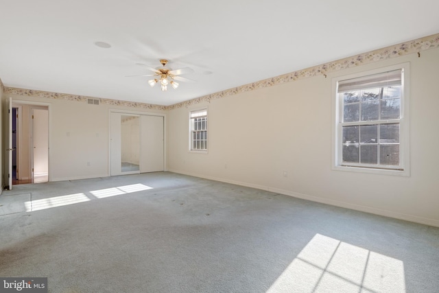 unfurnished room with ceiling fan, a healthy amount of sunlight, baseboards, and light carpet