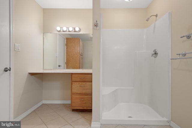 bathroom featuring vanity, tile patterned floors, a shower, and baseboards