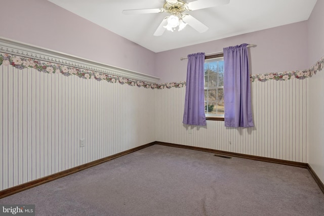 carpeted empty room featuring visible vents, ceiling fan, and baseboards