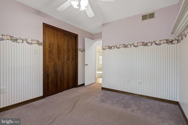 carpeted empty room with baseboards, visible vents, and ceiling fan