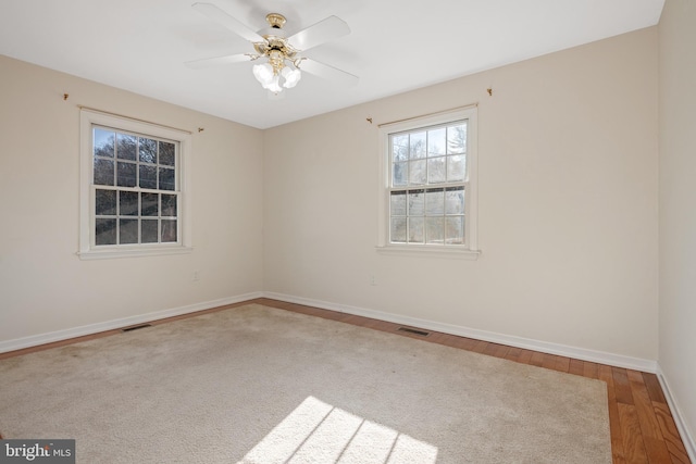 spare room with visible vents, ceiling fan, baseboards, and wood finished floors