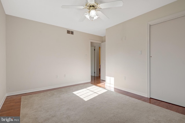 unfurnished bedroom featuring ceiling fan, wood finished floors, visible vents, and baseboards