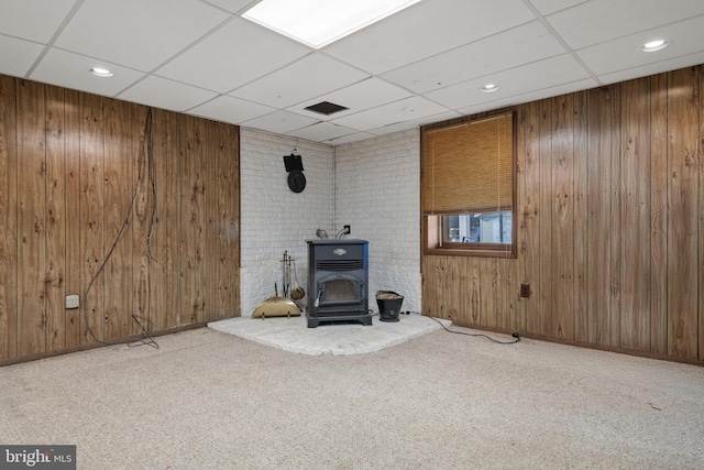 unfurnished living room featuring wood walls and carpet