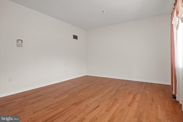 unfurnished room featuring visible vents, light wood-style flooring, and baseboards