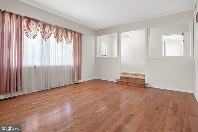 empty room featuring visible vents, baseboards, and light wood-style floors