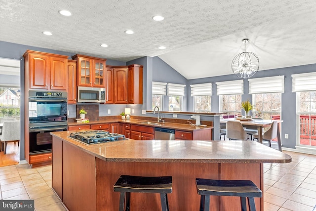 kitchen with a sink, appliances with stainless steel finishes, a wealth of natural light, and light tile patterned floors