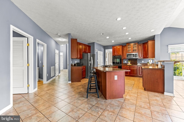 kitchen featuring a breakfast bar, light tile patterned floors, appliances with stainless steel finishes, and a kitchen island
