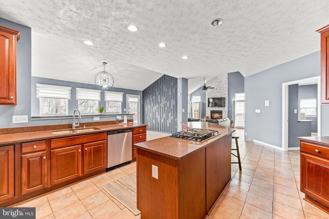 kitchen with vaulted ceiling, a fireplace, light tile patterned flooring, stainless steel appliances, and a sink