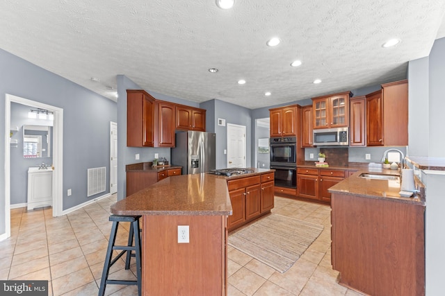 kitchen with visible vents, a breakfast bar, a sink, appliances with stainless steel finishes, and a center island
