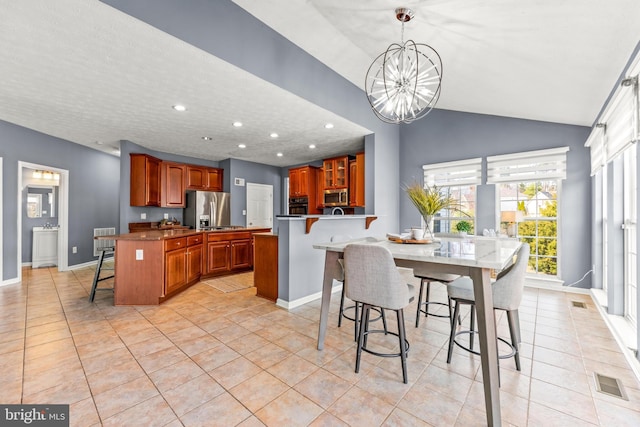 kitchen featuring light tile patterned floors, visible vents, a peninsula, stainless steel appliances, and a kitchen breakfast bar