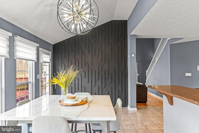 dining area with baseboards, stairs, a textured ceiling, an accent wall, and a chandelier